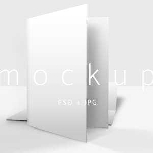 May include: A white, open booklet mockup with the word "mockup" in a light gray font. The text "PSD + JPG" is below the word "mockup". The booklet is standing upright on a white surface.