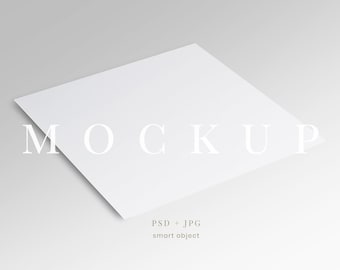 May include: A white square mockup with the word "MOCKUP" in a serif font. The text "PSD + JPG" and "smart object" are below the square. The background is a gradient of light gray.
