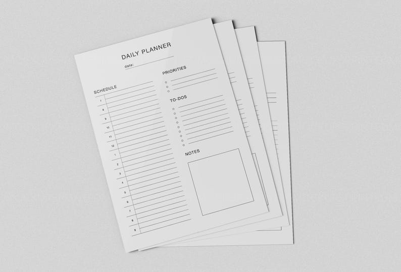 May include: A stack of white daily planner sheets with a minimalist design. Each sheet features sections for schedule, priorities, to-dos, and notes. The text "DAILY PLANNER" is at the top, with lines for date. The sheets are on a light gray background.