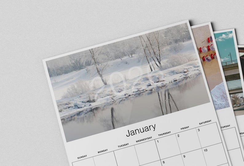 May include: A calendar featuring a winter landscape scene with a river and snow-covered trees. The month of January is displayed at the bottom, with the year 2024 faintly visible in the image. Additional calendar pages are visible.