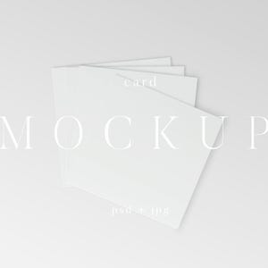 Puede incluir: Imagen de maqueta con una pila de tarjetas cuadradas blancas, ligeramente desplegadas. La palabra "MOCKUP" se muestra en una fuente delicada en las tarjetas, con "card" arriba y "psd + jpg" abajo. El fondo es gris claro y suave.