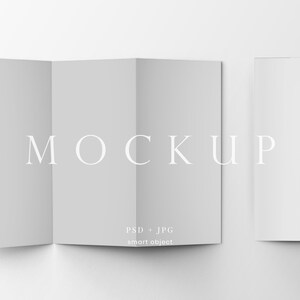 May include: A mockup of a brochure, tri-fold, and a single page, all in a light gray color. The word "MOCKUP" is printed in a light gray color. The text "PSD + JPG smart object" is printed below the word "MOCKUP".