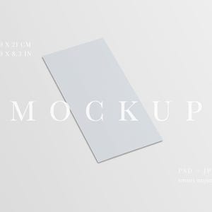 Può includere: Un mockup di carta rettangolare grigio chiaro, di 9,9 x 21 cm, è angolato su uno sfondo bianco. La parola "MOCKUP" è visualizzata in un carattere minimalista. L'immagine include anche testo che indica il tipo di file come PSD e JPG e l'oggetto è un oggetto intelligente.