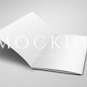 Puede incluir: Una maqueta de folleto blanco abierto con la palabra «MOCKUP» en una fuente grande y elegante. El texto «PSD + JPG» está debajo. El folleto está sobre una superficie gris claro, con una sombra.