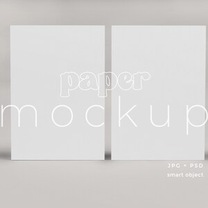 Könnte beinhalten: Zwei leere weiße Papierbögen, nebeneinander, mit dem Text "paper mockup" in weißen umrandeten Buchstaben.