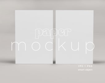 May include: Two blank white paper sheets, side by side, with the text "paper mockup" in white outlined letters.