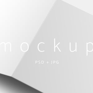 Könnte beinhalten: Ein weißes, offenes Karten-Mockup mit dem Wort "Mockup" in hellgrauer Schrift. Der Text "PSD + JPG" steht unter dem Wort "Mockup". Die Karte ist abgewinkelt, wobei Schatten dem Design Tiefe verleihen.