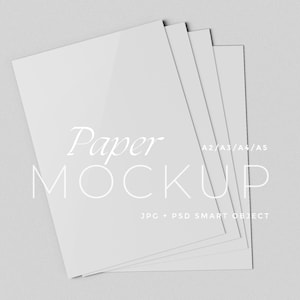 May include: A stack of white paper mockups, with the text "Paper MOCKUP" and "A2/A3/A4/A5" in a minimalist design. The image also includes the text "JPG + PSD SMART OBJECT". The papers are arranged in a fan shape.