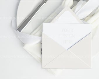 Op de afbeelding: Een witte envelop met een witte kaart erin. De kaart heeft de tekst "YOUR DESIGN HERE" erop gedrukt.