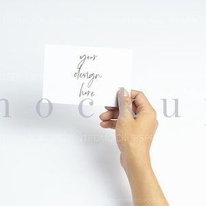 May include: A hand holding a blank white card with the text "your design here" written on it.