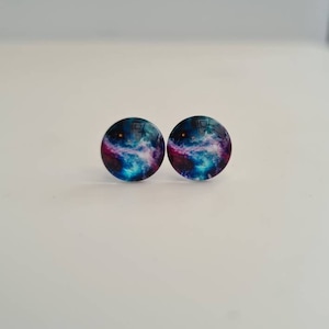 Op de afbeelding: Een paar galaxy-thema oorbellen met een blauw, paars en wit nevelontwerp.