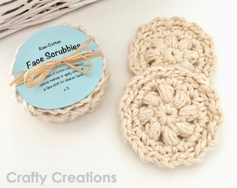 May include: Three crocheted cotton face scrubbies in a light beige colour. The scrubbies are packaged in a clear plastic bag with a blue label that reads "Raw Cotton Face Scrubbies" and "x3".