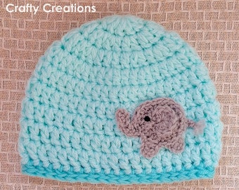 May include: A light blue crocheted baby hat with a gray crocheted elephant applique. The hat has a turquoise trim.