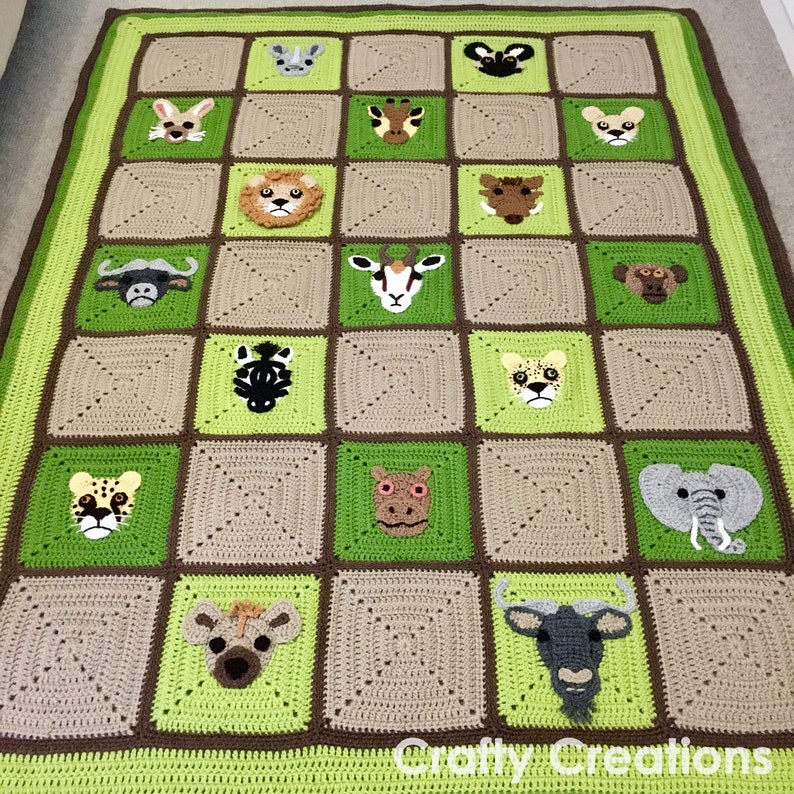 Puede incluir: Una manta de crochet con un esquema de color verde y marr&oacute;n que presenta varias caras de animales, incluyendo una cebra, un elefante, una jirafa y un le&oacute;n. La manta est&aacute; hecha de cuadrados, cada cuadrado presenta un animal diferente. La manta est&aacute; etiquetada como "Crafty Creations".