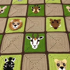 Puede incluir: Una manta de ganchillo con un patr&oacute;n de cuadros verdes y marrones. Cada cuadrado presenta una cara de animal diferente, incluyendo un le&oacute;n, una cebra, una jirafa, un rinoceronte, un guepardo, y m&aacute;s.
