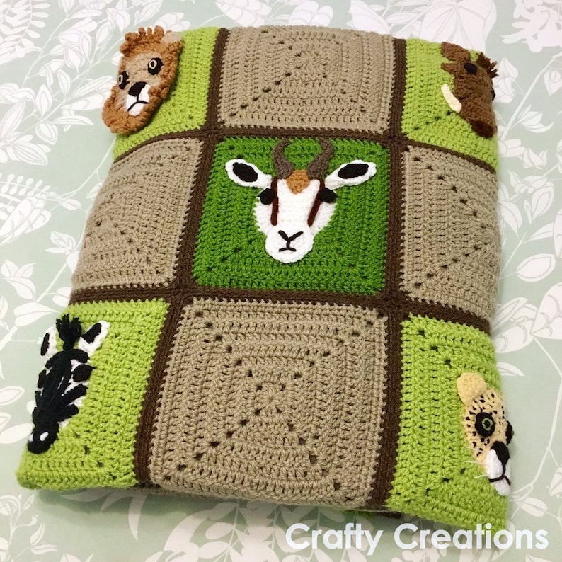 Puede incluir: Una manta de crochet verde y marr&oacute;n con varias aplicaciones de animales, incluyendo un le&oacute;n, una cebra, una ant&iacute;lope y un guepardo. La manta est&aacute; hecha de cuadrados con un borde marr&oacute;n.