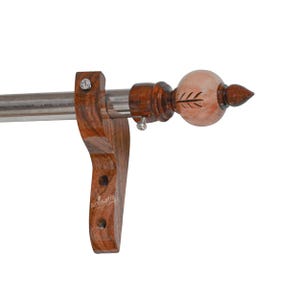 May include: A curtain rod with a decorative finial. The rod is made of stainless steel and is supported by a dark brown wooden bracket. The finial is light brown with a leaf design and a pointed tip.