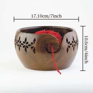 Pode incluir: Uma tigela de l&atilde; de madeira com um design floral esculpido e uma bola de l&atilde; vermelha. A tigela mede 17,8 cm de di&acirc;metro e 10,2 cm de altura.