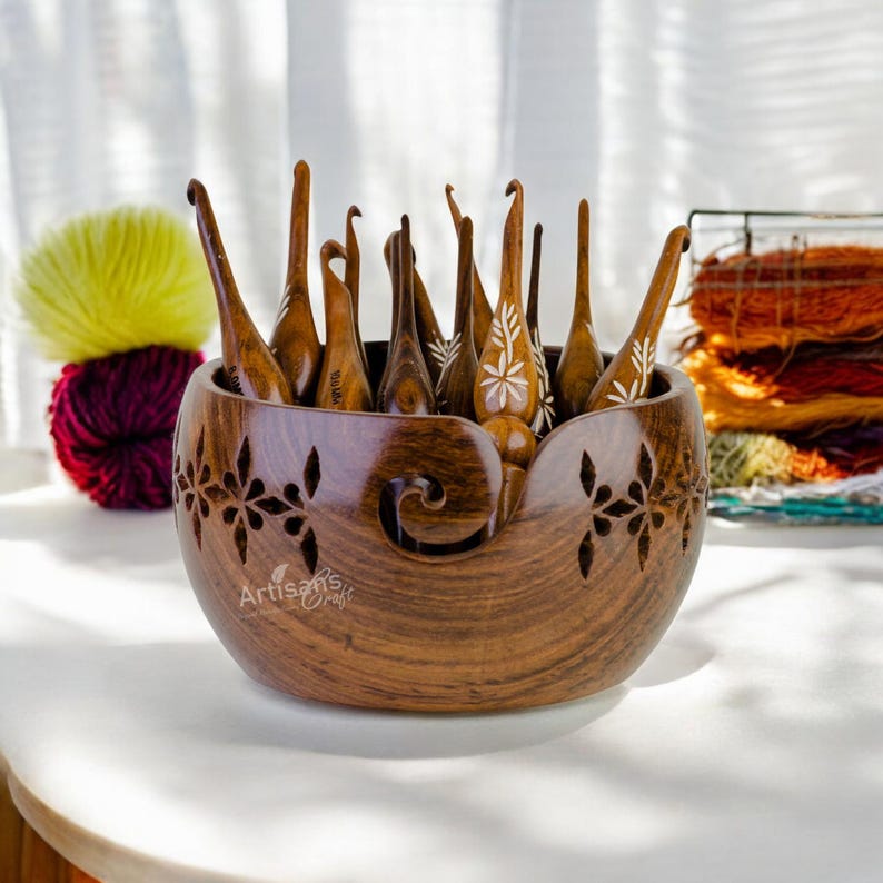 Pode incluir: Uma tigela de l&atilde; de madeira com entalhes intrincados e um design de espiral decorativo. A tigela est&aacute; cheia de uma variedade de ganchos de croch&ecirc; de madeira.