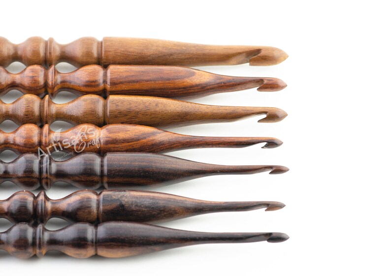 May include: Set of six wooden crochet hooks in various shades of brown. The hooks are arranged in a row, with the largest hook at the top and the smallest hook at the bottom.