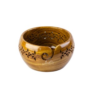 May include: A wooden yarn bowl with a carved design and a built-in yarn guide. The bowl is made of light brown wood with a natural finish.