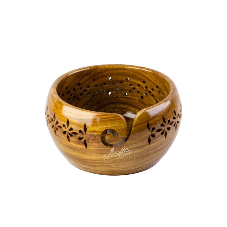 May include: A wooden yarn bowl with a carved design and a built-in yarn guide. The bowl is made of light brown wood with a natural finish.