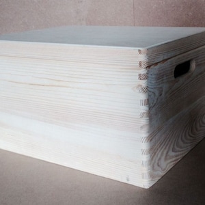 May include: A plain wooden box with a handle on the side. The box is made of light-coloured wood and has a natural finish.