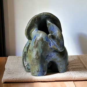 May include: A ceramic sculpture with a blue and green glaze. The sculpture is abstract and has a rounded, organic shape.