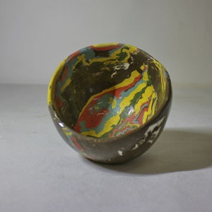 May include: A small, brown ceramic bowl with a marbled design in shades of yellow, red, blue, and green.