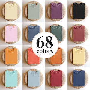 May include: A grid of folded t-shirts in various colors, including yellow, green, purple, black, pink, blue, and orange. The image features the text "68 colors" in a circular design, indicating a wide selection of available hues.