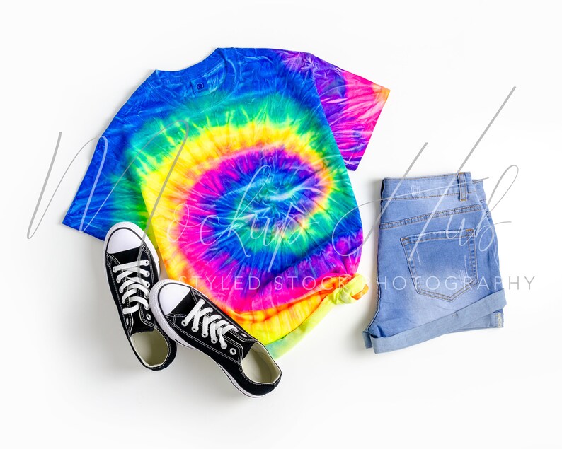May include: A tie-dye t-shirt with a rainbow swirl pattern, blue denim shorts, and black canvas sneakers.