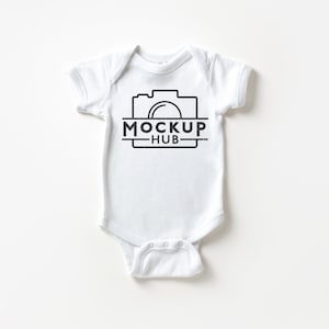 May include: A white baby onesie with short sleeves. The onesie features a black graphic of a camera with the text "MOCKUP HUB" below it. The onesie is designed for infants and is made of soft material.