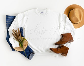 May include: White crew neck sweatshirt with long sleeves, blue jeans, brown leather boots, and a brown fedora hat on a white background.