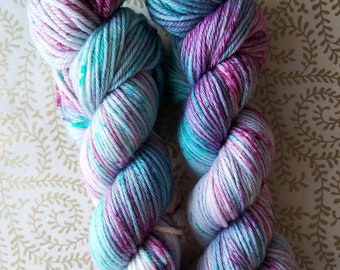 Puede incluir: Dos ovillos de hilo teñido a mano en una mezcla de morado, rosa, azul y blanco. El hilo es un color degradado con un efecto moteado.