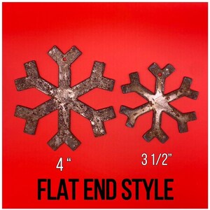 May include: Two rustic metal snowflake ornaments with a flat end style. The larger snowflake measures 4 inches, and the smaller one is 3.5 inches. The ornaments are displayed on a red background.