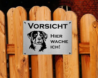 Könnte beinhalten: Ein silbernes Metallschild mit schwarzem Text und einer schwarzen Silhouette eines Hundes. Das Schild lautet "Vorsicht Hier Wache Ich!" was übersetzt "Vorsicht, ich wache hier!" bedeutet.
