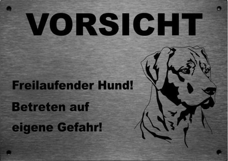 May include: A silver metal sign with black text that reads "Vorsicht Freilaufender Hund! Betreten auf eigene Gefahr!"  The sign also features a black silhouette of a dog's head.