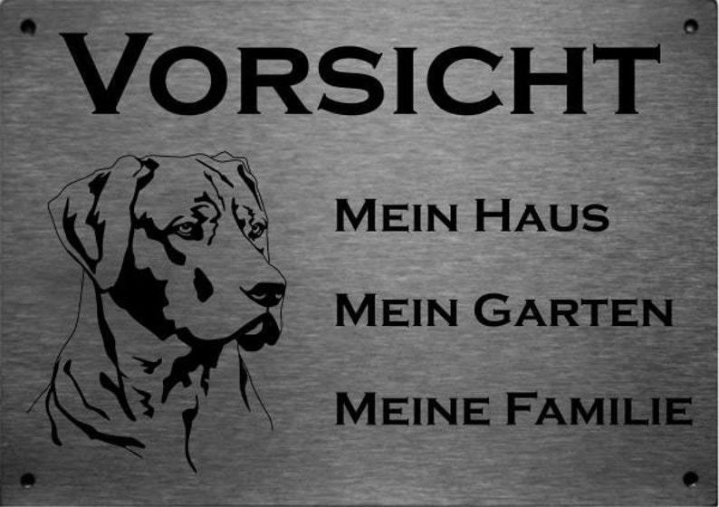 May include: A black and white sign with the text "Vorsicht" at the top. Below the text is a silhouette of a dog's head. The text "Mein Haus", "Mein Garten", and "Meine Familie" are printed below the dog's head.