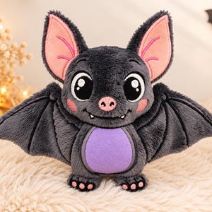 May include: A plush bat toy with dark gray fur, large black eyes, and pink inner ears. It features a purple belly patch, small pink nose, and two white fangs. The wings are spread wide, and the feet have small pink paw pads on the soles.
