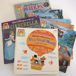 Puede incluir: Una pila de libros de cuentos de Walt Disney vintage con un formato de libro y cinta. Los libros presentan personajes clásicos de Disney como Peter Pan, Cenicienta y el Zorro y el Sabueso. Cada libro tiene una portada colorida con ilustraciones de los personajes y un título que dice "La historia de Walt Disney..." y "Es un mundo pequeño".