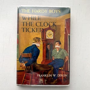Vintage Hardy Boys Book #11 While The Clock Ticked / Orange Endpapers 40s-50s Edition with Dust Jacket | Franklin W. Dixon | Grosset Dunlap