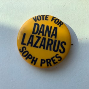 May include: Yellow button with black text that reads "Vote for Dana Lazarus Soph Pres".