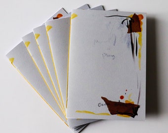 May include: A stack of six gray paperbacks with yellow edges. The top book has a brown and orange abstract design and the text "Memory of Play" and "Elen" written on it.