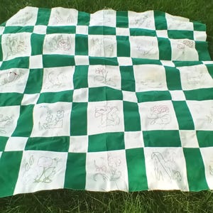 May include: A quilt top featuring a checkerboard pattern of solid green squares and white squares. Each white square contains a delicate, hand-stitched embroidery design depicting various floral and botanical motifs in thin, dark thread lines.