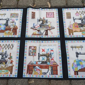 May include: A black fabric panel featuring six framed illustrations of sewing machines and sewing supplies. Each illustration has a white background with a decorative border. The sewing machines are depicted on tables with various sewing accessories.
