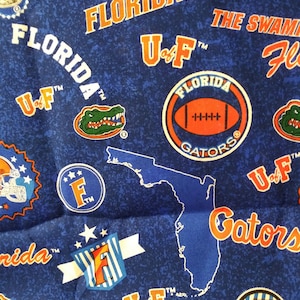 May include: Blue fabric with a repeating pattern of the University of Florida Gators logo, including the mascot alligator, the team's name, and the state of Florida. The fabric also features the team's colors, orange and blue.