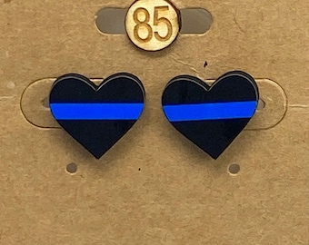 May include: A pair of black heart-shaped earrings with a thin blue stripe across the center. The earrings are on a brown card with the number 85.