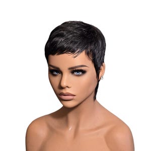 May include: A mannequin head with a short, black pixie cut wig. The wig has a textured appearance and is styled with a side part. The mannequin has blue eyes, dark eyelashes, and is wearing small, silver earrings.