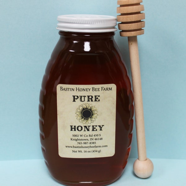 1 LB Local Indiana honey in a glass jar with a wooden honey dipper.