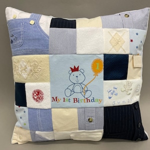 May include: A blue and white patchwork pillow with a teddy bear design and the text "My 1st Birthday".